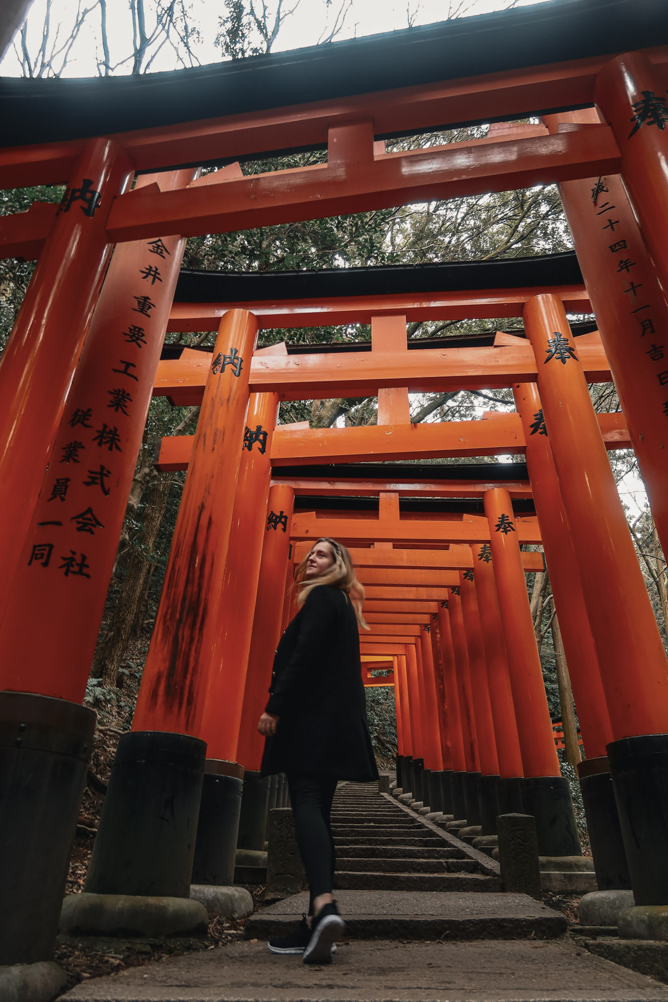 Tara Oh Reilly walking through orange tori gates of Fushimi Inari hike