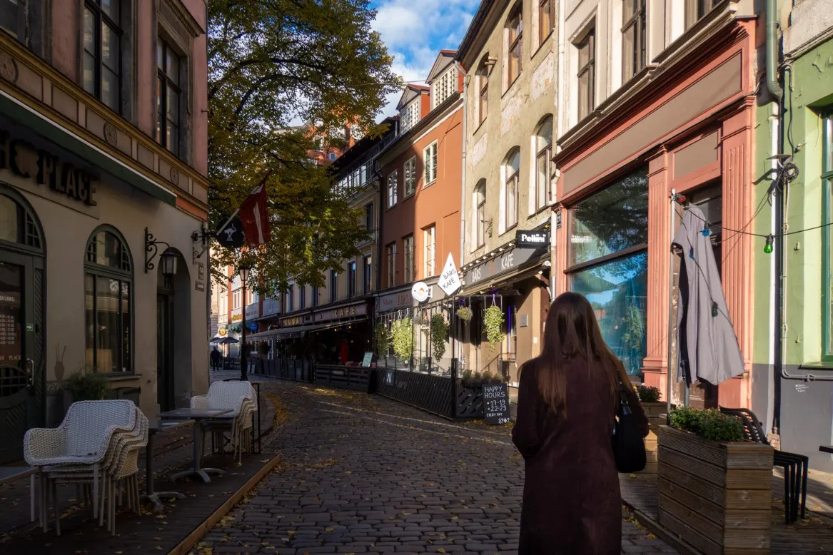 woman walking down colourful riga old town street